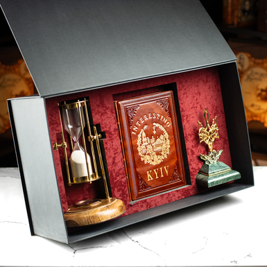 The gift set includes the book "Interesting Kiev," a vintage hourglass "Royal Compass - 1953," a custom-made figurine of the Coat of Arms of Ukraine, the Trident, and a gift box